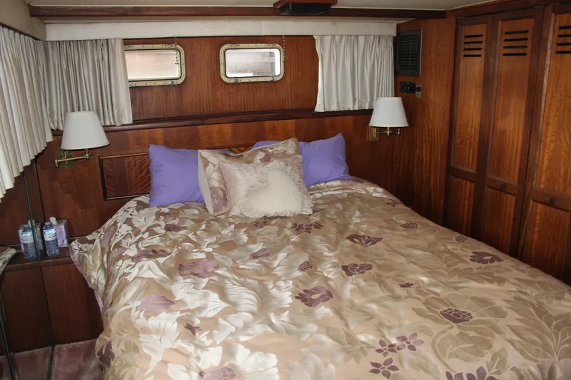 Apple 1 Yacht Photos Pics Luxurious bedroom interior of 1974 Hatteras 58 Yachtfish with floral bedding and wood paneling.