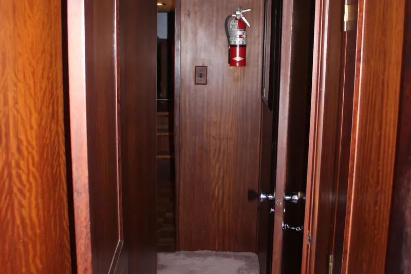 Apple 1 Yacht Photos Pics Wood-paneled hallway inside 1974 Hatteras 58 Yachtfish, featuring a fire extinguisher.