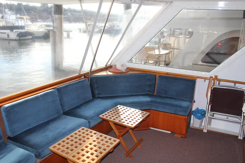 Apple 1 Yacht Photos Pics 1974 Hatteras 58 Yachtfish interior with blue seating and wooden tables, docked at marina.
