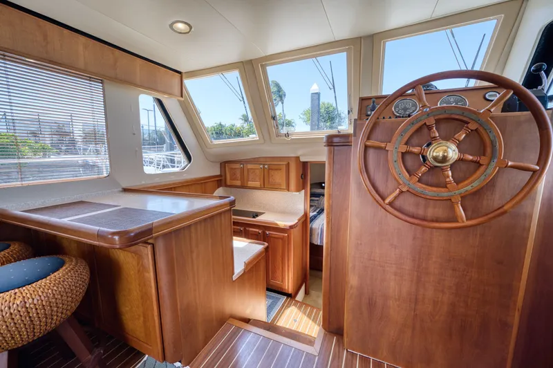 Oasis Yacht Photos Pics Interior of a 2006 Mainship 34 Trawler with wood paneling and steering wheel.
