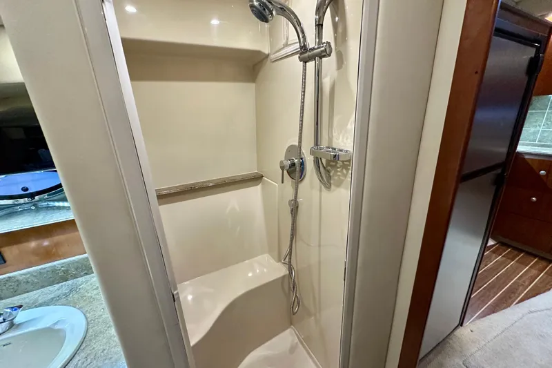 Somewhere With You Yacht Photos Pics 2009 Cruisers Yachts 460 Express bathroom with shower, sink, and wooden cabinetry.