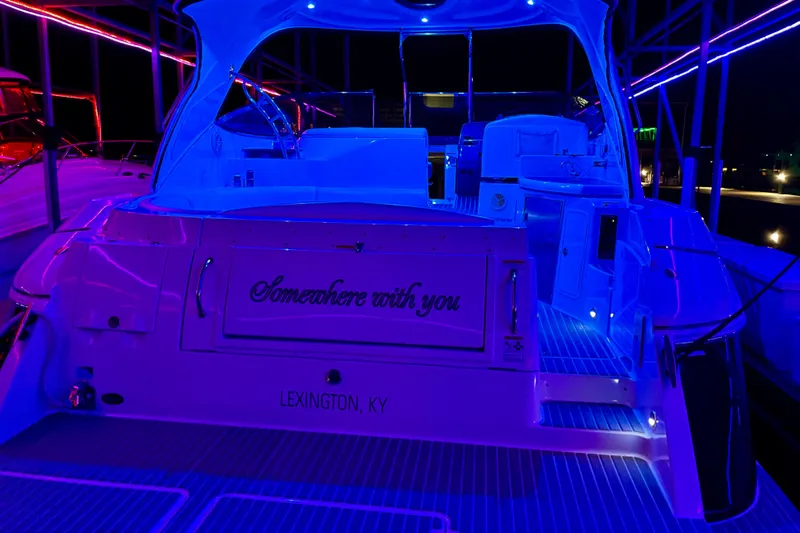 Somewhere With You Yacht Photos Pics 2009 Cruisers Yachts 460 Express with vibrant blue and purple lighting at night.