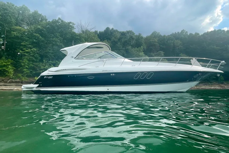 Somewhere With You Yacht Photos Pics 2009 Cruisers Yachts 460 Express on serene water with lush forest backdrop.