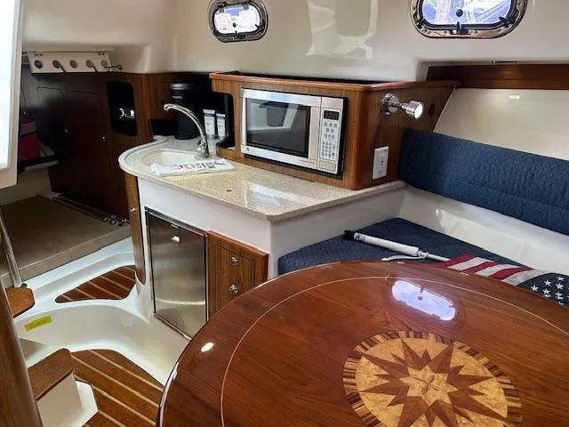  Yacht Photos Pics 2012 Pursuit OS 315 Offshore cabin with kitchenette, microwave, seating, and wooden table.