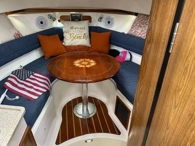  Yacht Photos Pics 2012 Pursuit OS 315 Offshore cabin with cozy seating, wooden table, and decorative pillows.