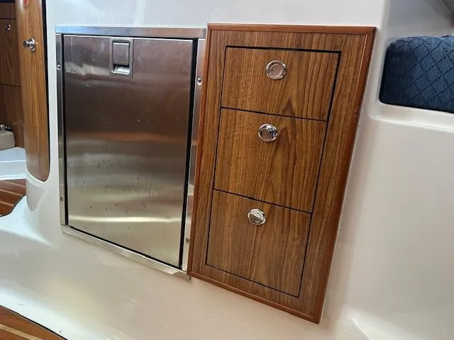  Yacht Photos Pics 2012 Pursuit OS 315 Offshore interior with stainless steel fridge and wooden storage drawers.