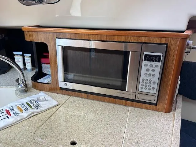  Yacht Photos Pics Microwave in 2012 Pursuit OS 315 Offshore boat kitchen, with wooden cabinetry and countertop.