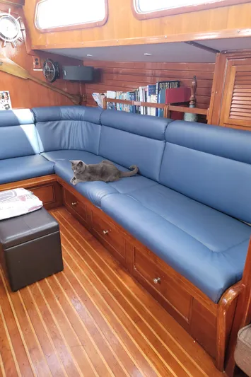 Magic Carpet Yacht Photos Pics 1983 Challenger Custom 60 yacht interior with blue seating and a cat lounging.