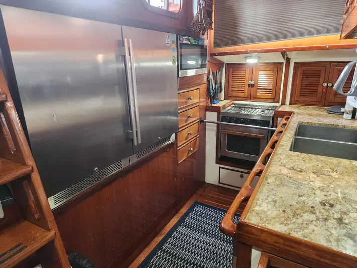 Magic Carpet Yacht Photos Pics 1983 Challenger Custom 60 yacht kitchen with stainless steel appliances and wooden cabinetry.