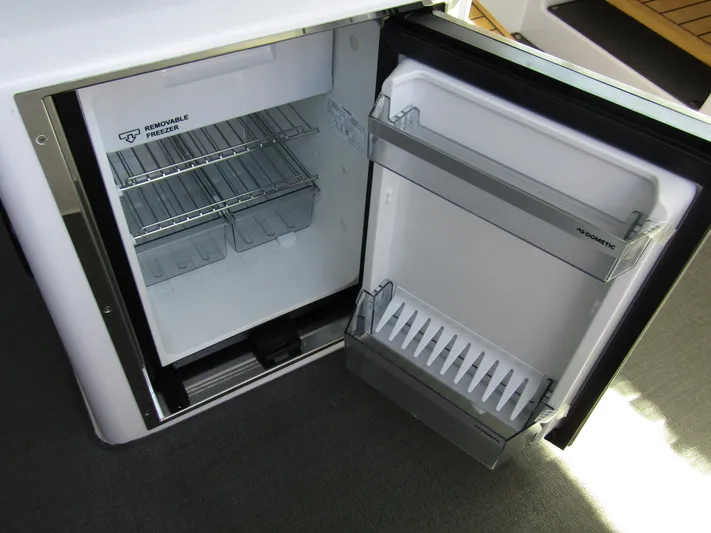  Yacht Photos Pics Open refrigerator inside 2025 Axopar 37XC CROSS CABIN, showcasing storage shelves and compartments.