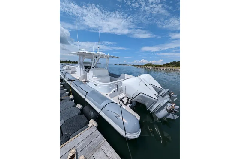 Yellowfin Yacht Photos Pics 2015 Yellowfin RIB boat docked on calm water under a blue sky.
