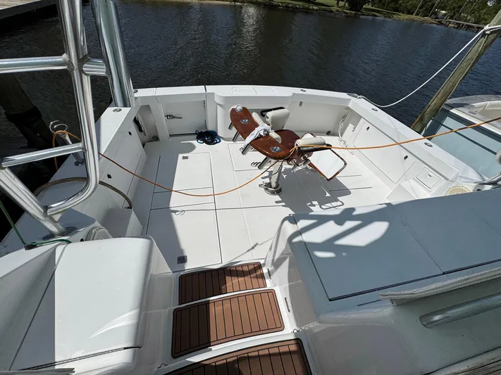  Yacht Photos Pics 1999 Cabo 45 Express boat deck with fishing chair, docked by the water.