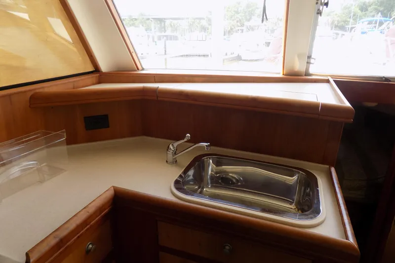  Yacht Photos Pics 2004 Mainship 390 Trawler kitchen area with sink and wooden cabinetry.