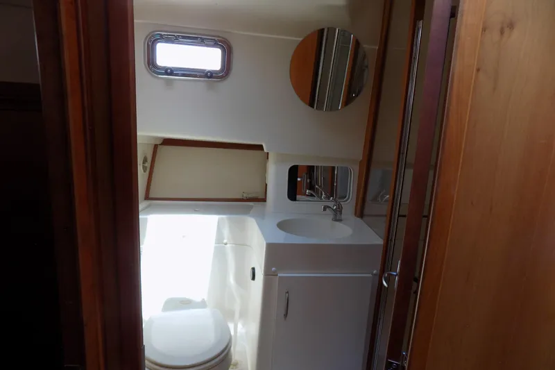  Yacht Photos Pics Bathroom interior of 2004 Mainship 390 Trawler with sink, toilet, and porthole window.