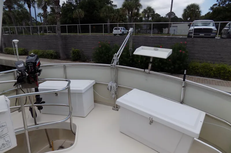  Yacht Photos Pics 2004 Mainship 390 Trawler deck with storage boxes and motor, docked near greenery.