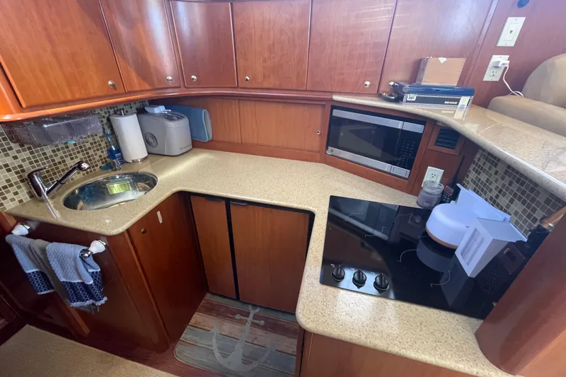 Born Free Yacht Photos Pics 2007 Silverton 38 Convertible yacht kitchen with sink, stove, microwave, and wooden cabinetry.