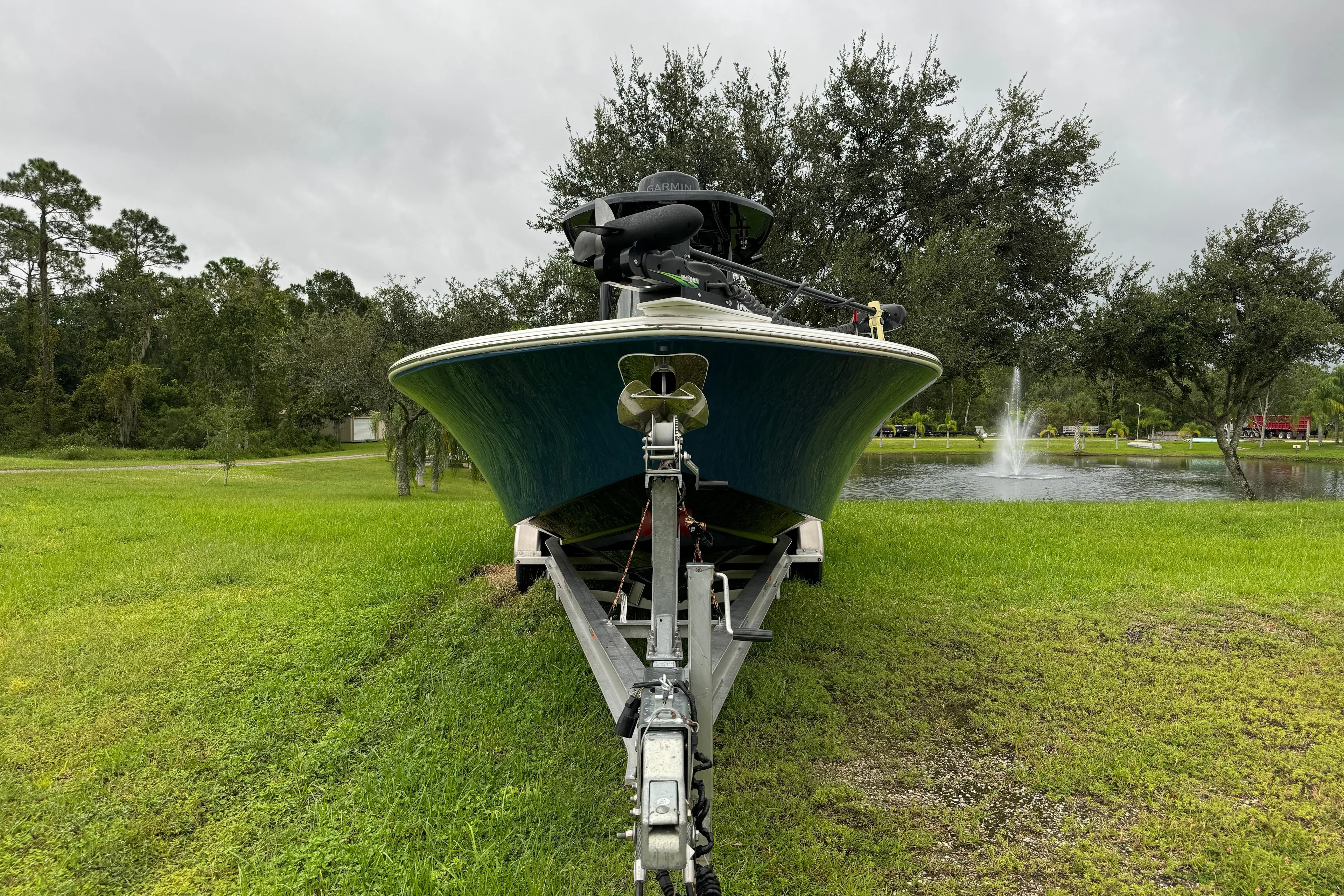  Yacht Photos Pics 2023 Tidewater 2700 Carolina Bay boat on trailer, parked near a pond with fountain.