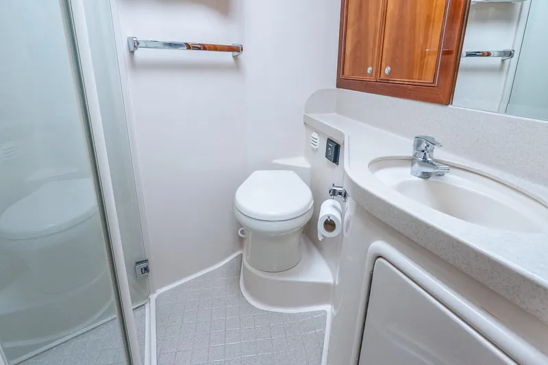 Chillax Yacht Photos Pics 2005 Riviera 51 Flybridge bathroom with toilet, sink, and wooden cabinet.