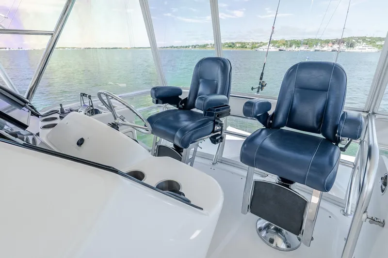 Chillax Yacht Photos Pics 2005 Riviera 51 Flybridge helm with blue captain chairs overlooking serene waters.