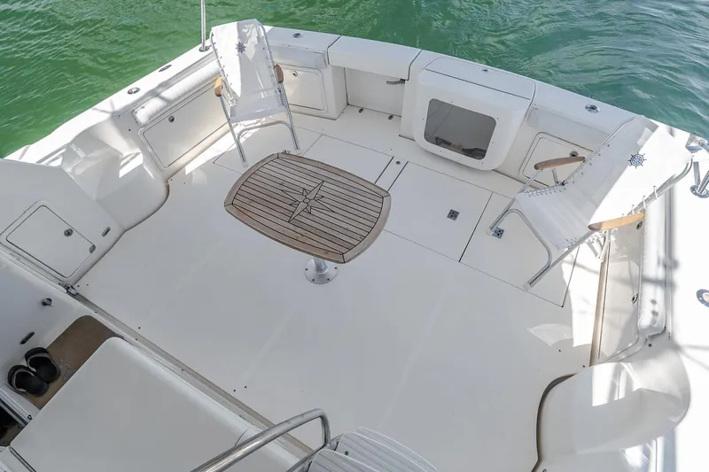 Chillax Yacht Photos Pics Spacious deck of 2005 Riviera 51 Flybridge with chairs and wooden table.