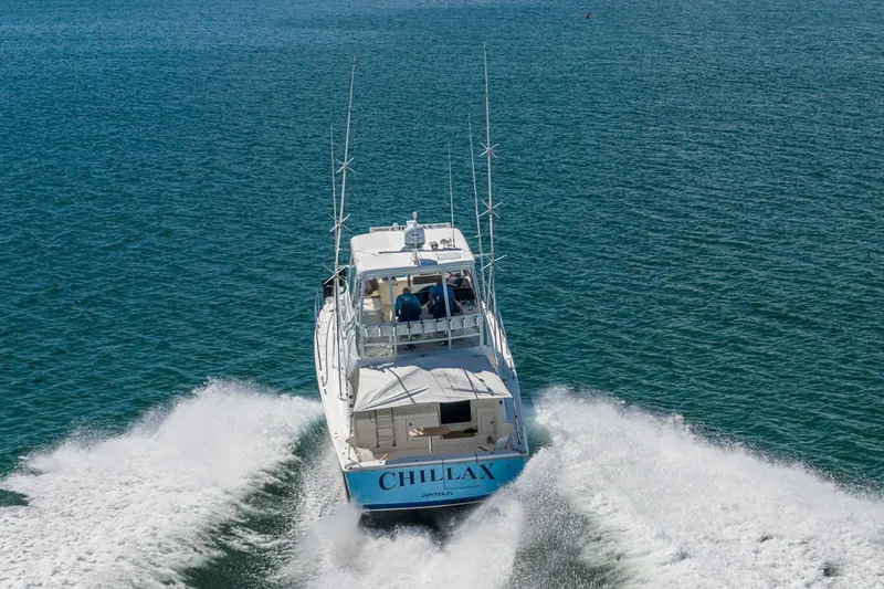 Chillax Yacht Photos Pics 2005 Riviera 51 Flybridge yacht cruising on open water, rear view.