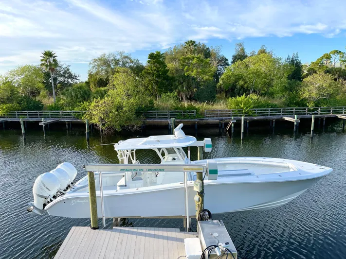  Yacht Photos Pics 2022 Yellowfin 34 boat docked on a serene river with lush greenery.