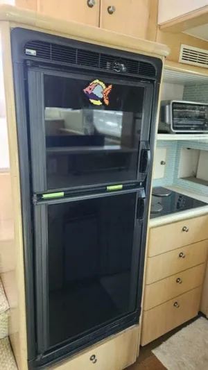 Elusive Yacht Photos Pics 1997 Carver 500 Cockpit Motor Yacht kitchen with black fridge and wooden cabinets.