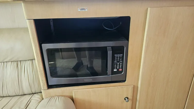 Elusive Yacht Photos Pics Microwave in 1997 Carver 500 Cockpit Motor Yacht interior, set in wooden cabinetry.