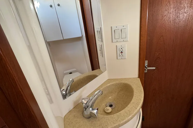 Dark And Stormy Yacht Photos Pics Bathroom sink area in 2000 Tiara Yachts 3500 Express, featuring mirror and wooden door.