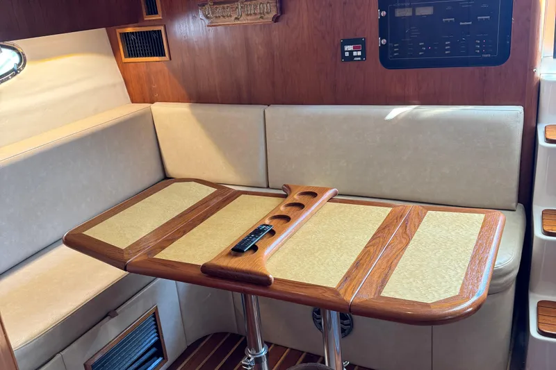 Dark And Stormy Yacht Photos Pics Interior of 2000 Tiara Yachts 3500 Express with wooden table and beige seating.
