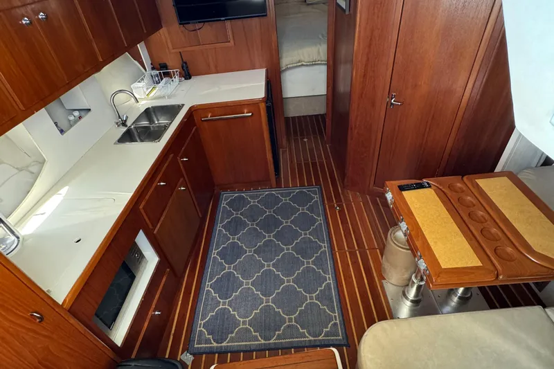 Dark And Stormy Yacht Photos Pics Interior of 2000 Tiara Yachts 3500 Express with wood cabinetry and compact kitchen.