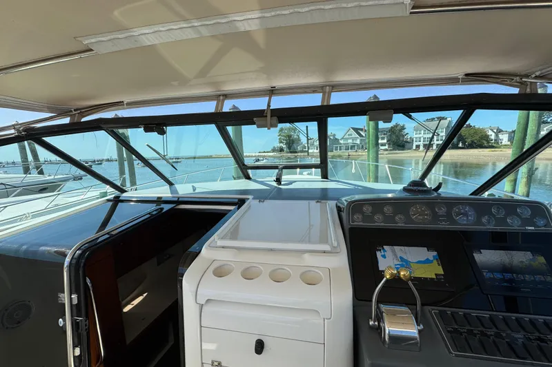 Dark And Stormy Yacht Photos Pics 2000 Tiara Yachts 3500 Express cockpit with navigation controls, docked by waterfront homes.