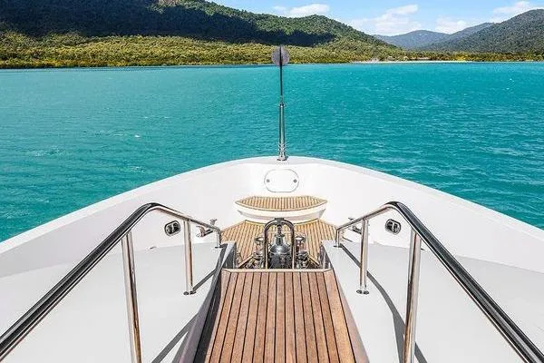 Batavia Yacht Photos Pics Bow view of 2003 Richmond Yachts 135 Motor Yacht on turquoise water, surrounded by lush hills.