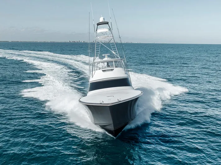 Bid Time Yacht Photos Pics 2023 Viking 72 Convertible yacht cruising swiftly on open ocean waters.