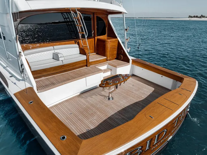 Bid Time Yacht Photos Pics 2023 Viking 72 Convertible yacht with spacious teak deck and seating, cruising on clear blue water.