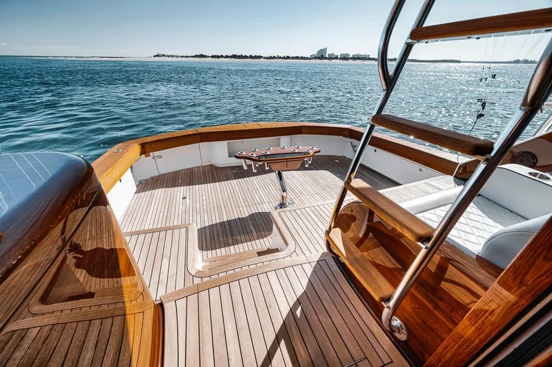 Bid Time Yacht Photos Pics 2023 Viking 72 Convertible yacht deck with wooden finish, overlooking serene ocean waters.