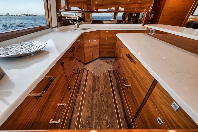 Bid Time Yacht Photos Pics Luxurious kitchen interior of 2023 Viking 72 Convertible yacht with wooden cabinetry and ocean view.