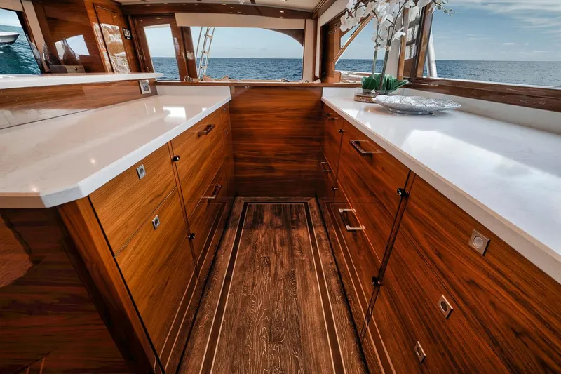 Bid Time Yacht Photos Pics Luxurious interior of 2023 Viking 72 Convertible yacht with wooden cabinetry and ocean view.