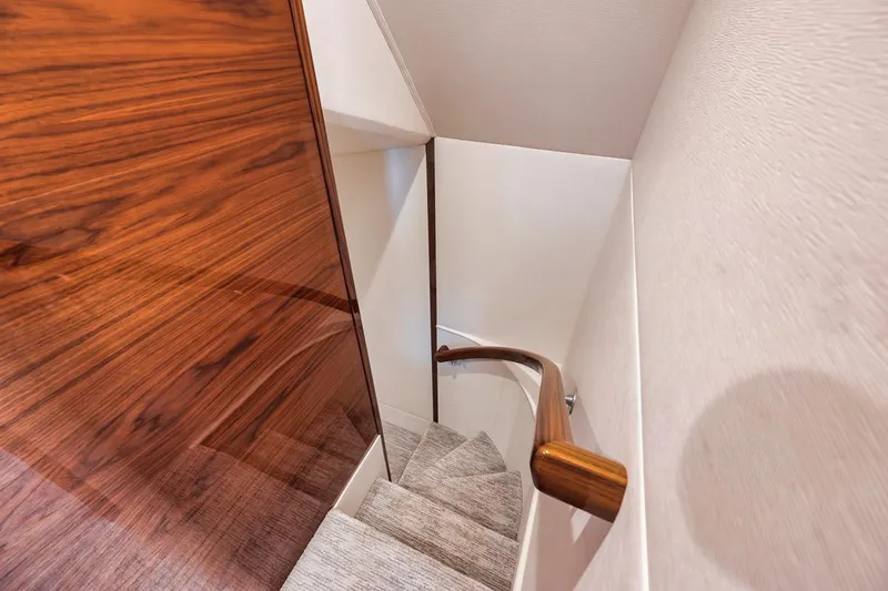 Bid Time Yacht Photos Pics Staircase inside 2023 Viking 72 Convertible yacht with wooden paneling and sleek design.