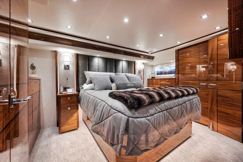 Bid Time Yacht Photos Pics Luxurious bedroom interior of 2023 Viking 72 Convertible yacht, featuring elegant wood finishes.