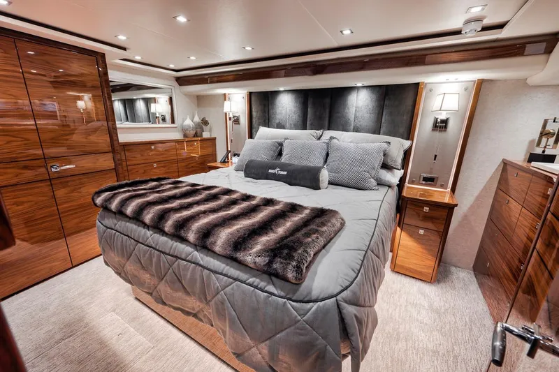 Bid Time Yacht Photos Pics Luxurious bedroom interior of 2023 Viking 72 Convertible yacht with elegant wood finishes.