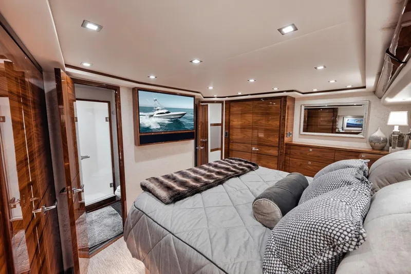 Bid Time Yacht Photos Pics Luxurious bedroom interior of 2023 Viking 72 Convertible yacht with modern decor and wood finishes.