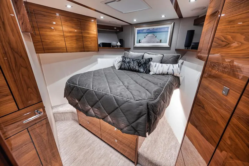 Bid Time Yacht Photos Pics Luxurious bedroom interior of 2023 Viking 72 Convertible yacht with wood finishes and modern decor.