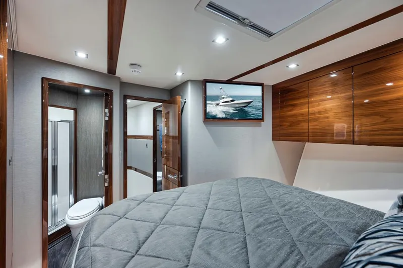 Bid Time Yacht Photos Pics Luxurious bedroom interior of 2023 Viking 72 Convertible yacht with ensuite bathroom.