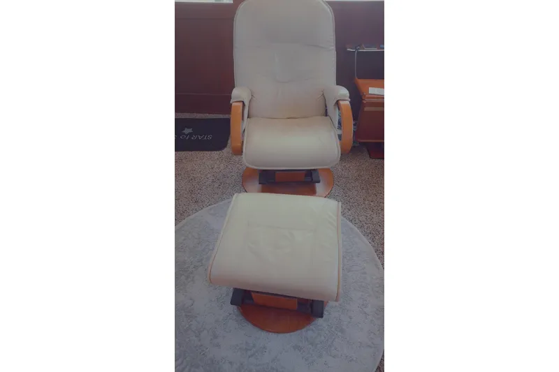  Yacht Photos Pics Cream recliner chair with matching footrest on a circular rug in a cozy room.