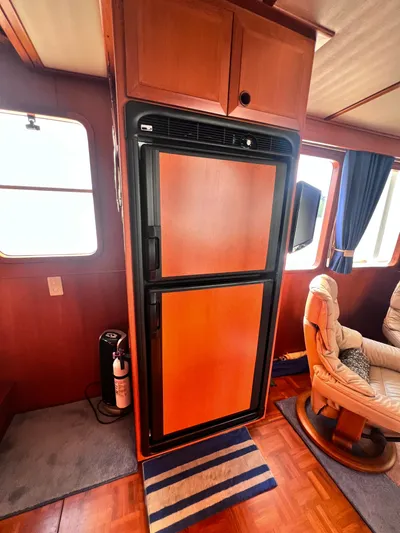 Xanadu Yacht Photos Pics 2006 DeFever Pilothouse interior with wooden cabinetry, refrigerator, and comfortable seating.