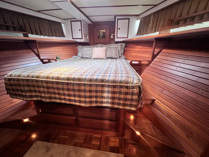 Xanadu Yacht Photos Pics Luxurious 2006 DeFever Pilothouse bedroom with wood paneling and cozy bedding.