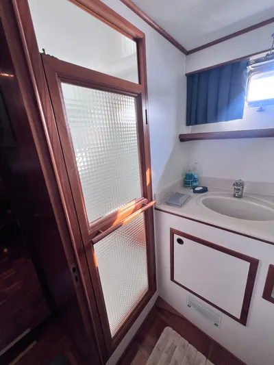 Xanadu Yacht Photos Pics 2006 DeFever Pilothouse bathroom with sink, frosted glass door, and wooden accents.