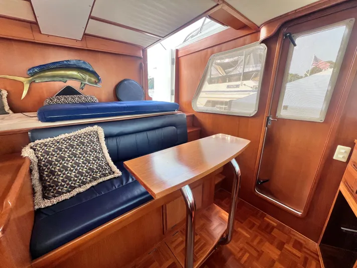 Xanadu Yacht Photos Pics 2006 DeFever Pilothouse interior with wooden table, blue seating, and decorative fish wall art.