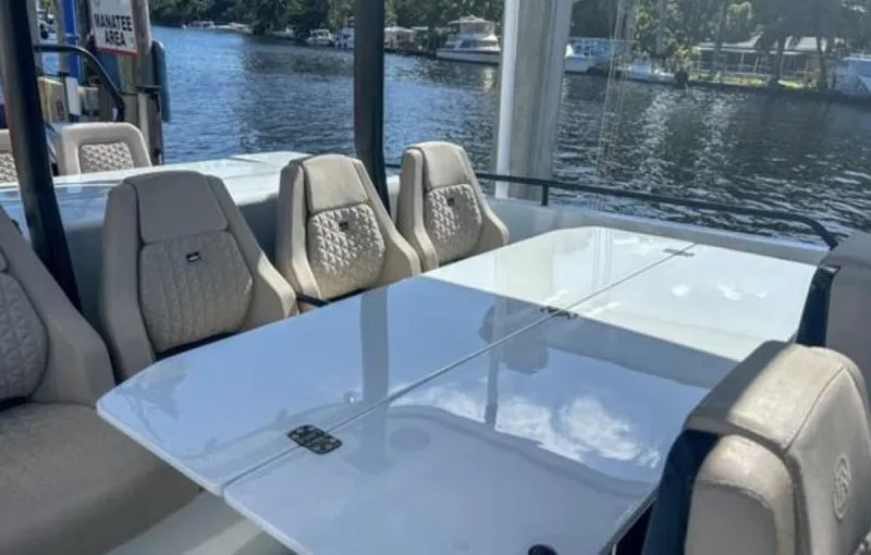 Kraken Yacht Photos Pics 2023 BRABUS Shadow 900 yacht interior with elegant seating and table, docked by a scenic river.